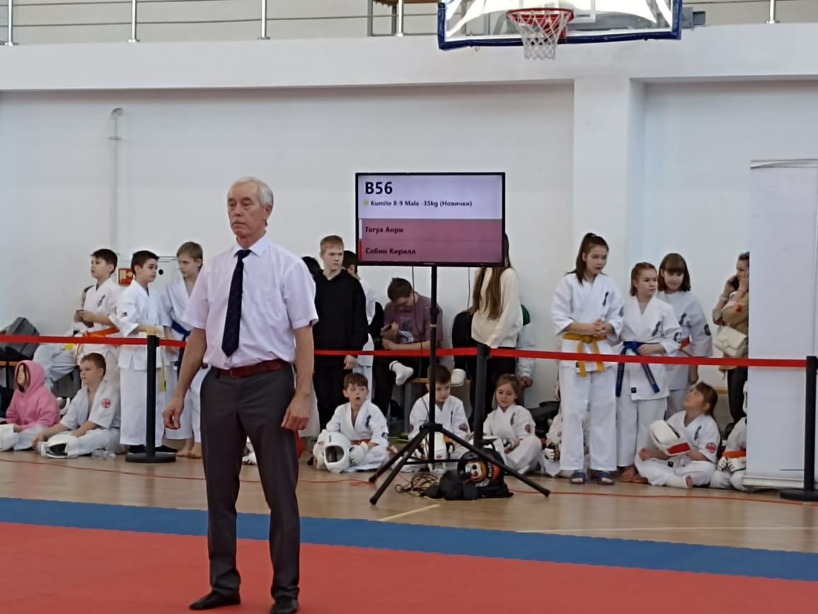Қоңыр белдікті судья: B56 Гогуа — Собени, қызыл лентаның жанында басқауы бар балалар Кубок побратим балалар турниріндегі татамидық қазы: кимоно киген балалар, B56 кумитэ жұбын көрсететін табло